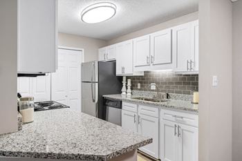 The kitchen features granite counters, white cabinets and the laundry closet.